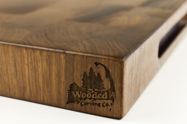 Wooden cutting board with 'Wooded Carving Co.' branding on a white background