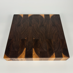 End-grain walnut cutting board with a dark brown and light brown pattern on a white background