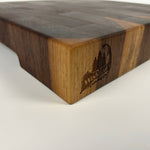 End-grain walnut cutting board with a dark brown and light brown pattern with a engraved logo on a white background