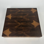 Thick walnut end-grain cutting board top-down view on white background