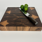 Thick Wooden walnut end-grain cutting board with a knife and limes on a white background