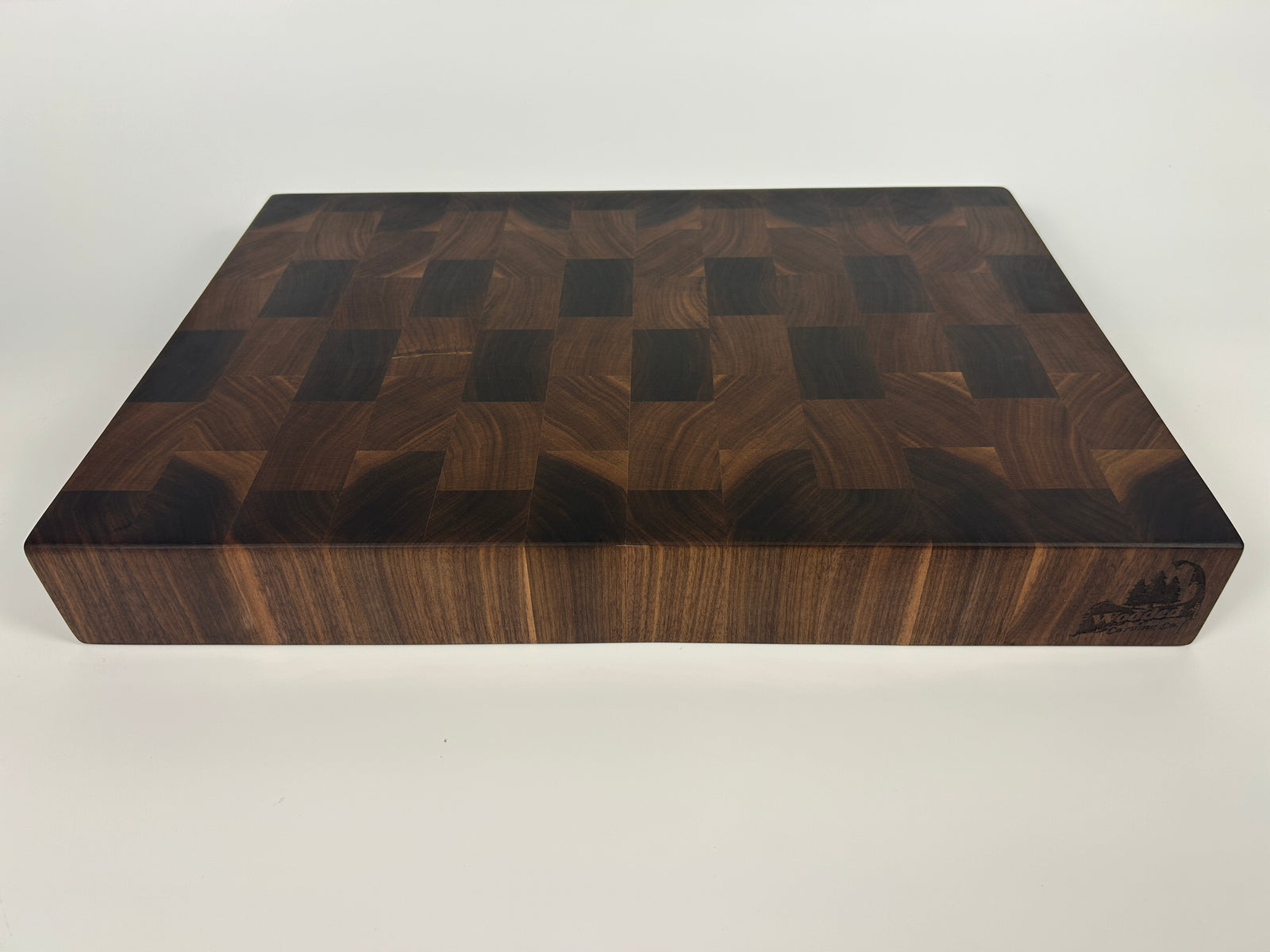 Thick, Walnut end grain cutting board with a knife and limes on a white background