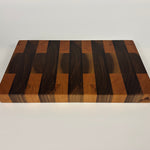 End grain Walnut and Cherry cutting board with a striped pattern on a white background