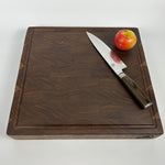 Walnut wood cutting board with a knife and an apple on a white background