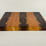 End grain cherry and walnut cutting board with a distinct striped pattern on a white background