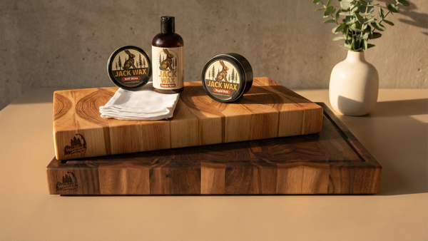 Three Jack Wax products on wooden cutting boards with a vase of greenery in the background.