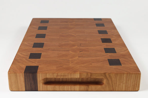 Wooden cutting board with black square patterns on a white background