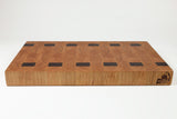 Wooden cutting board with black square holes on a white background