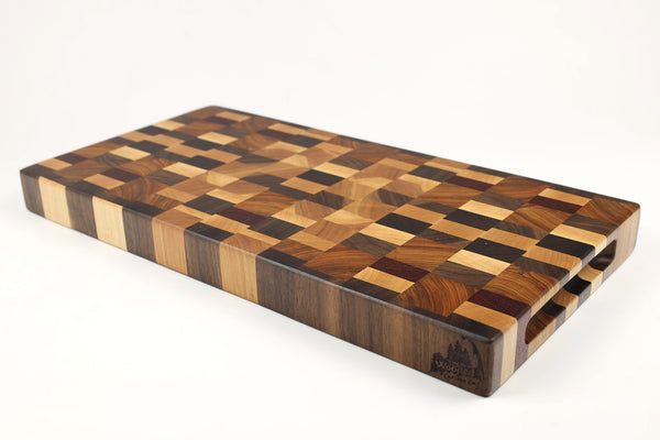 Mid-angle hero shot of Chaos Quilt  — Maple, Walnut, Cherry, Padauk, and Canarywood end-grain cutting board, 9.5″ × 19.5″ × 1.5″