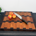 Wooden cutting board with apples and a knife on a dark surface