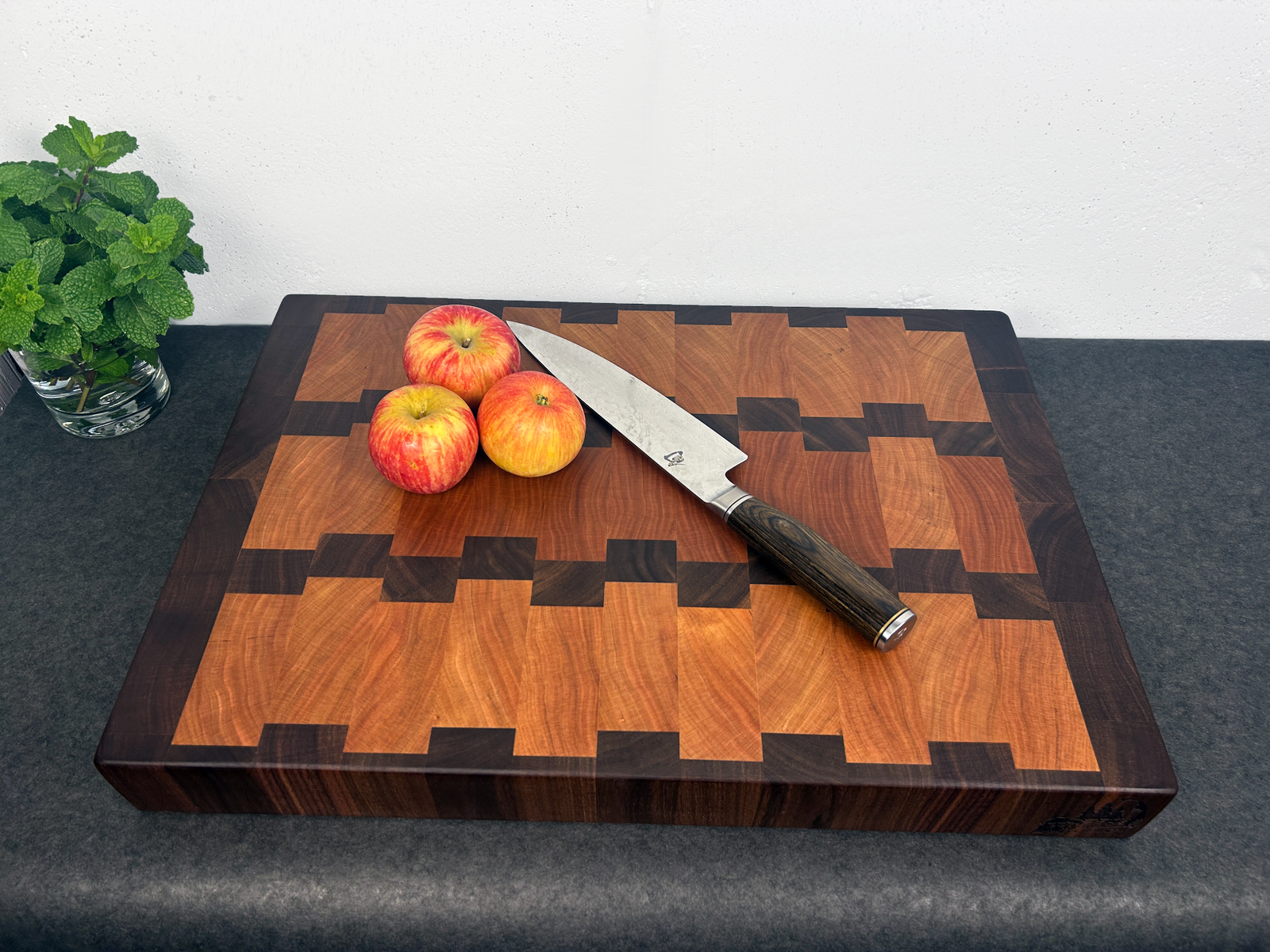 Wooden cutting board with apples and a knife on a dark surface